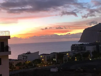 a sunset over the ocean with buildings and a mountain at Pérola - Madeira Inn Group in Funchal