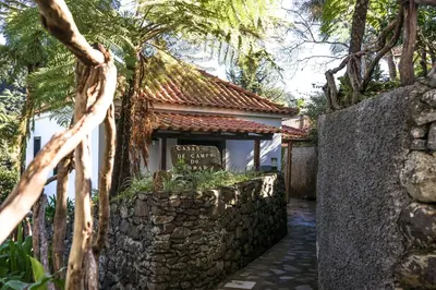 a walkway leading to a building with a stone wall at Casas de Campo do Pomar B&B - Self Check-in in Santana