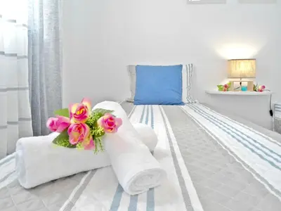a white bedroom with a bed with towels and flowers at Funchal Apartment in Funchal