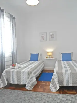 two beds in a white room with blue pillows at Funchal Apartment in Funchal