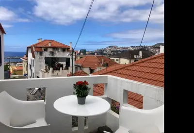 a white table and chairs on a balcony with a view at Casa do Atlântico in Funchal
