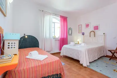 a bedroom with two beds and a table and a window at Villa Paraiso da Luz by Seewest in Luz