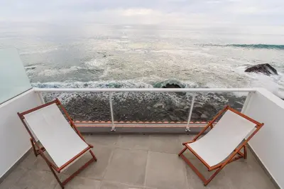 two chairs on a balcony looking out at the ocean at Casa das bonecas 2 # Private Garage Included # in Paul do Mar