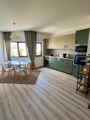 a living room with a table and a kitchen at Apartamentos Sol da Luz in Luz