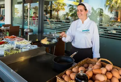 a woman preparing food in a restaurant kitchen at VidaMar Resort Hotel Madeira in Funchal