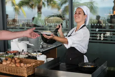 a woman in a kitchen holding a plate of food at VidaMar Resort Hotel Madeira in Funchal