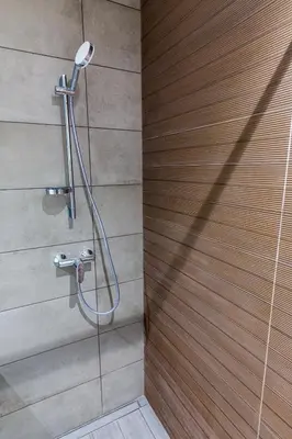 a shower in a bathroom with a wooden wall at Sea Breeze I in Caniço
