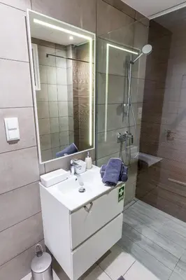 a bathroom with a sink and a shower with a mirror at Sea Breeze I in Caniço