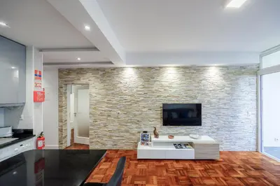 a living room with a brick wall with a tv at Sea Breeze I in Caniço