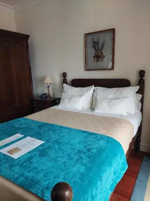 a bedroom with a large bed with a blue blanket at Estalagem do Vale in São Vicente