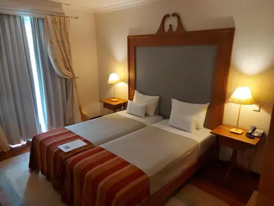 a hotel room with a large bed with two lamps at Estalagem do Vale in São Vicente