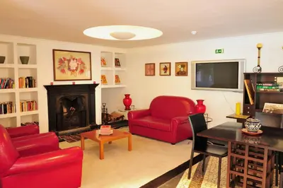 a living room with red chairs and a fireplace at Estalagem do Vale in São Vicente