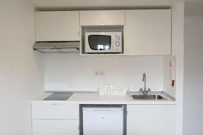 a white kitchen with a microwave and a sink at Florasol Residence Hotel - Dorisol hotels in Funchal