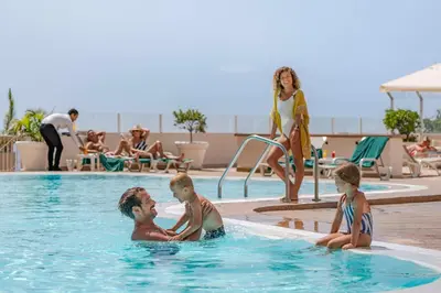 a man and two children playing in a swimming pool at Florasol Residence Hotel - Dorisol hotels in Funchal