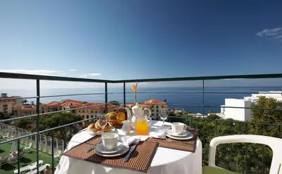 a tall building with a palm tree in front of it at Florasol Residence Hotel - Dorisol hotels in Funchal