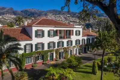 an aerial view of a large white building with green shutters at Quinta Jardins do Lago in Funchal