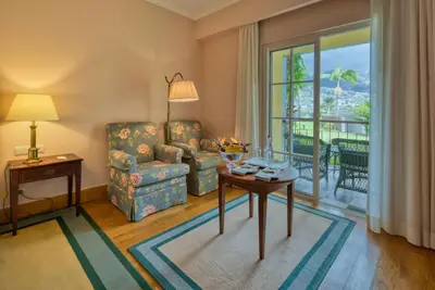 a living room with a chair and a table and a window at Quinta Jardins do Lago in Funchal