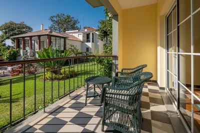 a balcony with two chairs and a table and a table at Quinta Jardins do Lago in Funchal