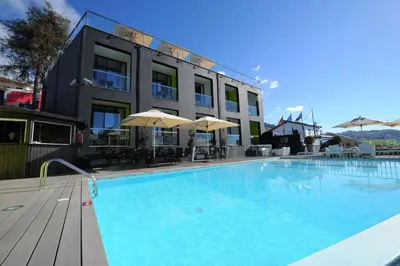 a patio with white chairs and a swimming pool at Quinta Mirabela - Design Hotel in Funchal
