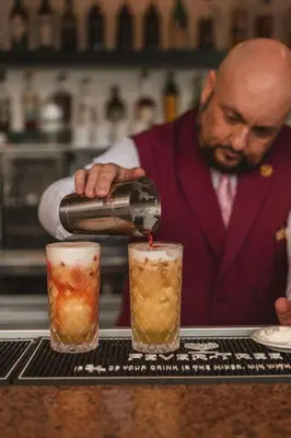 a man pouring a drink into two cocktails at Royal Savoy - Ocean Resort - Savoy Signature in Funchal