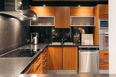 a kitchen with wooden cabinets and stainless steel appliances at Royal Savoy - Ocean Resort - Savoy Signature in Funchal