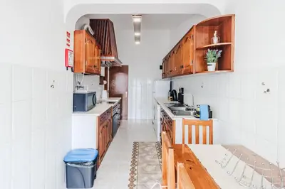 a kitchen with wooden cabinets and a blue stool at Casa da Avó in Espiche