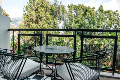 a table and chairs on a balcony with trees at Quintinha Sao Joao Hotel & Spa in Funchal