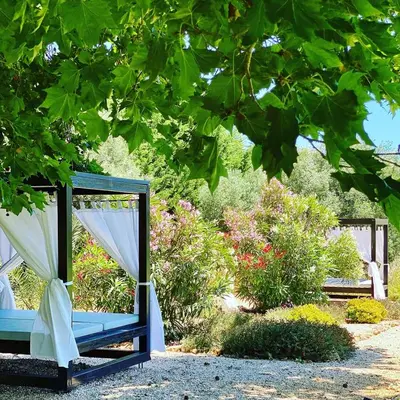 a blue bench sitting in a garden under a tree at Vila Valverde Design Country Hotel in Luz