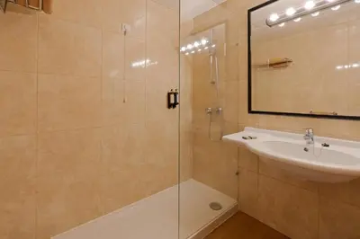 a bathroom with a shower and a sink and a mirror at Dom Pedro Garajau in Caniço