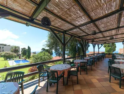 a row of tables and chairs on a patio at Dom Pedro Garajau in Caniço