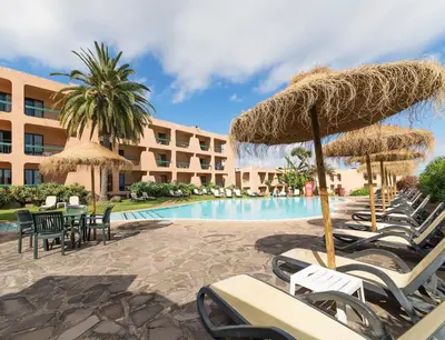 a resort with a swimming pool with chairs and umbrellas at Dom Pedro Garajau in Caniço