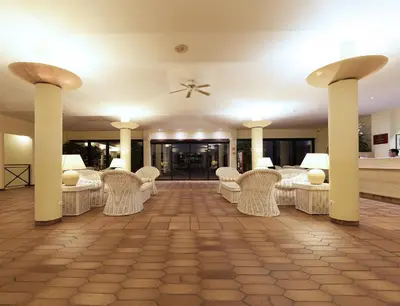 a room with white chairs and tables and columns at Dom Pedro Garajau in Caniço