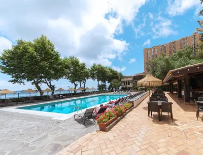 a pool at a hotel with people sitting at tables at Dom Pedro Madeira in Machico
