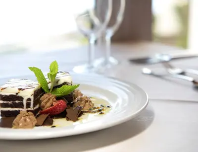 a piece of cake on a white plate on a table at Dom Pedro Madeira in Machico