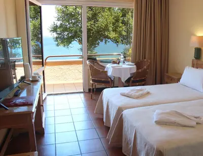 a hotel room with two beds and a table with a view at Dom Pedro Madeira in Machico