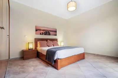 a bedroom with a bed and two lamps on a tiled floor at Sunny Ponta 
