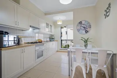 a kitchen with white cabinets and a table and chairs at Sunny Ponta 
