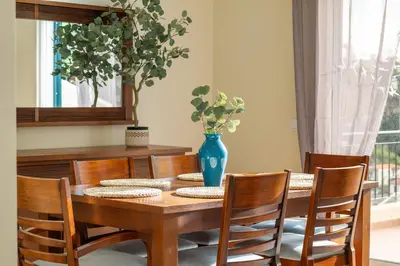 a dining room table with chairs and a blue vase on it at Sunny Ponta 