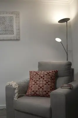 a gray couch with a red pillow and a lamp at ANGEL´S SUNSET in Estreito da Calheta