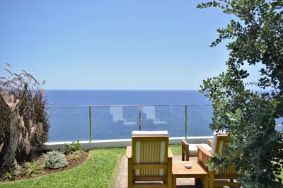 a balcony with a table and chairs and the ocean at Madeira Regency Cliff - Adults Only in Funchal