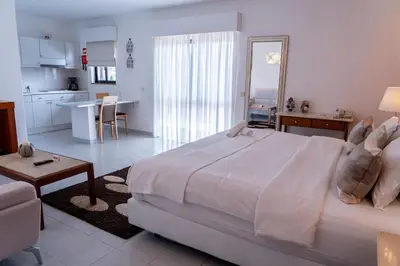 a bedroom with a large white bed and a kitchen at Villa Mar Azul in Lagos