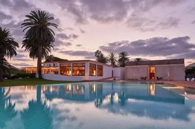 a house with a swimming pool in front of a building at Hotel Porto Santo & Spa in Porto Santo