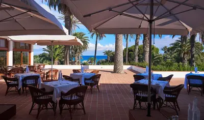 a restaurant with tables and chairs and umbrellas at Hotel Porto Santo & Spa in Porto Santo