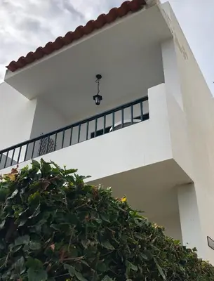 a white house with a staircase and a hedge at Porto Santo Apartment in Porto Santo
