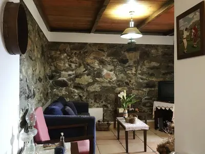 a living room with a couch and a stone wall at Casa d'Olívia in Porto da Cruz