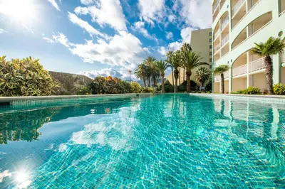 a swimming pool with blue water in front of a building at Pestana Ocean Bay Resort in Funchal
