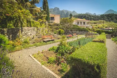a garden with a bench and a house in the background at Solar da Bica in São Vicente