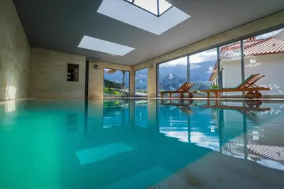 a swimming pool with two chairs in a house at Solar da Bica in São Vicente