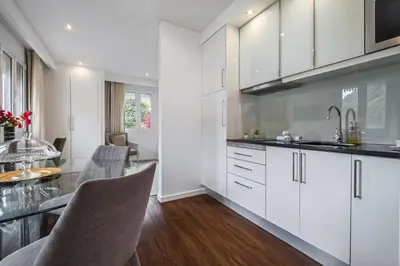 a kitchen with white cabinets and a glass table at Quinta da Tia Briosa by Homie in Ponta do Sol