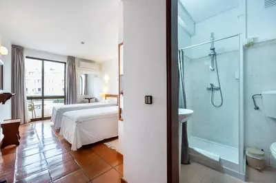 a bedroom with a bed and a shower and a bathroom at Salema Beach Hotel in Salema